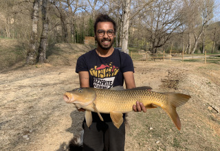 Lachende man met grote vis bij Flower Camping La Rivière in Provence-Alpes-Côte d’Azur, Frankrijk.