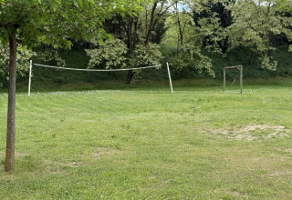 Buitensportveld bij Flower Camping La Rivière in Provence met volleybalnet en voetbaldoel in het gras.
