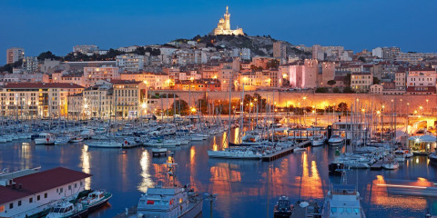 Vue du port de plaisance illuminé au crépuscule à Provence-Alpes-Côte d’Azur, France, avec bateaux et ville.