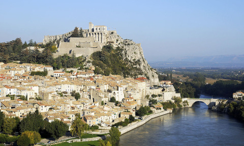 Vista de Flower Camping La Rivière en Provence-Alpes-Côte d’Azur, Francia, con río y castillo en la colina.