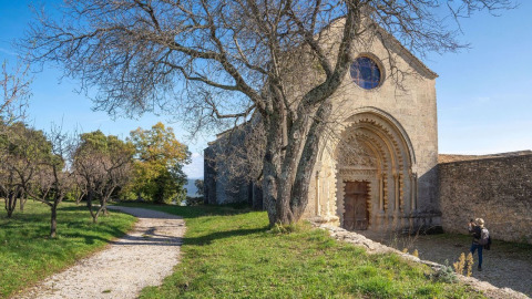Edificio de piedra con entrada arqueada y árboles sin hojas en Flower Camping La Rivière, Provenza-Alpes-Costa Azul, Francia.