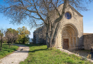Stenbygning med buet indgang og nøgne træer ved Flower Camping La Rivière i Provence-Alpes-Côte d’Azur, Frankrig.