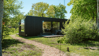 Casa moderna nera immersa nella natura ad Ark Shelter, parco vacanze De Klepperstee, Paesi Bassi.