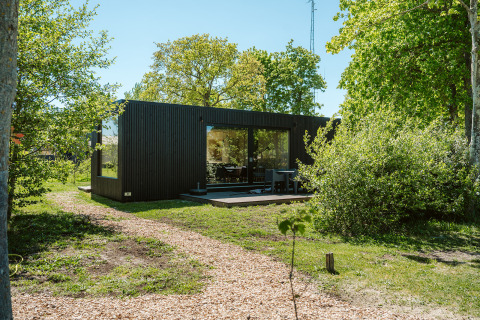 Moderne sort hytte i grønne omgivelser ved Ark Shelter, feriepark De Klepperstee, Nederlandene.