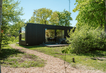 Casa moderna nera immersa nella natura ad Ark Shelter, parco vacanze De Klepperstee, Paesi Bassi.
