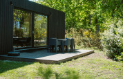 Ark Shelter natuurhuis met houten terras en stoelen te midden van groen in De Klepperstee, Nederland.