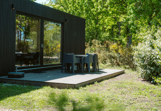 Ark Shelter nature house with deck and outdoor seating surrounded by greenery at De Klepperstee, Netherlands.