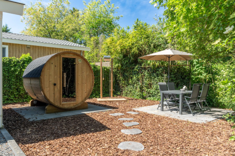 Jardin du Wellness Cottage à De Thijmse Berg, sauna privé, coin repas extérieur et verdure luxuriante.