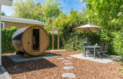 Jardín del Wellness Cottage en De Thijmse Berg con sauna privada, mesa exterior y vegetación abundante.