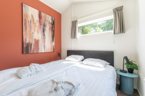 Moderne soveværelse i Wellness Cottage på De Thijmse Berg med stort maleri og vindue med udsigt.