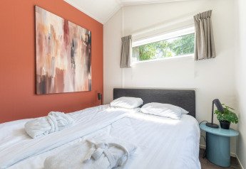 Schlafzimmer im Wellness Cottage, De Thijmse Berg, mit Kunst an der Wand und Tageslichtfenster.