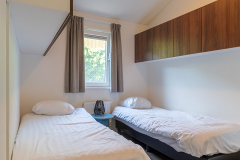 Chambre lumineuse dans le Wellness Cottage à De Thijmse Berg, Pays-Bas, avec lits jumeaux et armoires bois.