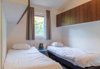 Lyst soveværelse i Wellness Cottage på De Thijmse Berg i Holland med to enkeltsenge og træskabe.