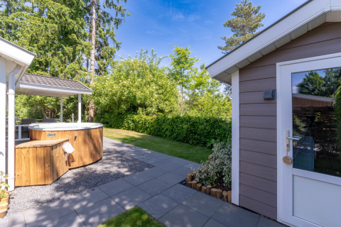 Espace extérieur du Wellness Cottage avec jacuzzi privé et sauna à De Thijmse Berg, Pays-Bas, journée ensoleillée.