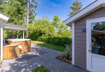 Outdoor area of Wellness Cottage with private hot tub and sauna at De Thijmse Berg, Netherlands, sunny day.