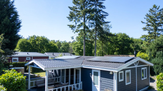 Heuvelrug Cottage avec jacuzzi à De Thijmse Berg aux Pays-Bas, entouré de verdure et d’arbres.