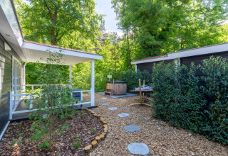 Área exterior de la Wellness Lodge en De Thijmse Berg, Países Bajos, rodeada de vegetación frondosa.