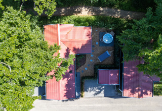 Vista aérea de Wellness Lodge en De Thijmse Berg, Países Bajos, con tejados rojos y jardín arbolado.