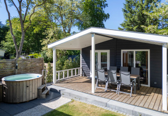 Familiehytte med overdækket terrasse og udendørs spabad ved De Thijmse Berg, omgivet af grøn natur.