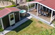Udsigt over Family Lodge og spabad på De Thijmse Berg i Holland med terrasse, havemøbler og græsplæne.