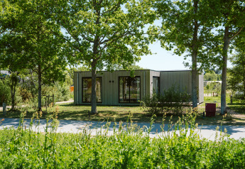 Duunroos lodge in vakantiepark De Klepperstee in Nederland, omgeven door bomen en groene natuur.
