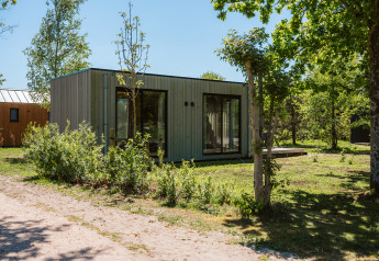 Moderne lodge bij vakantiepark De Klepperstee in Nederland, omgeven door bomen en groen.
