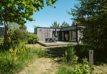 Houten natuurhuis met terras en groene tuin bij Huus van Hanse, vakantiepark De Klepperstee, Nederland.