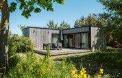 Moderna casa natural en Holiday park De Klepperstee, rodeada de árboles y naturaleza en los Países Bajos.