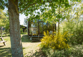 Wikkel tiny house au Holiday park De Klepperstee, Pays-Bas, entourée d’arbres et de verdure.