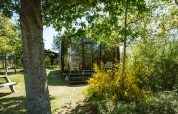 Wikkel tiny house en Holiday park De Klepperstee, Países Bajos, rodeada de árboles y vegetación.