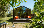 Modern natuurhuisje bij vakantiepark De Klepperstee, Oep, Nederland, omringd door groene bomen en zonlicht.