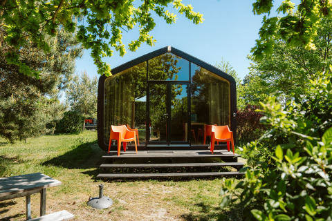 Modern natuurhuisje bij vakantiepark De Klepperstee, Oep, Nederland, omringd door groene bomen en zonlicht.