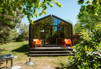 Modern natuurhuisje bij vakantiepark De Klepperstee, Oep, Nederland, omringd door groene bomen en zonlicht.