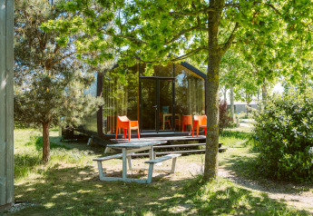 Maison nature moderne à De Klepperstee avec grandes baies vitrées, chaises orange et table de pique-nique.
