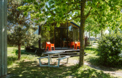 Casa moderna de naturaleza en De Klepperstee con ventanas grandes, sillas naranjas y mesa de picnic al aire libre.