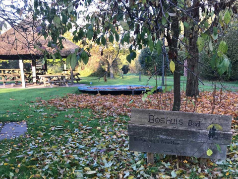 Autumn scene at Feather Down Het Boshuis, Gelderland, Netherlands, with garden, wooden sign, and playground.
