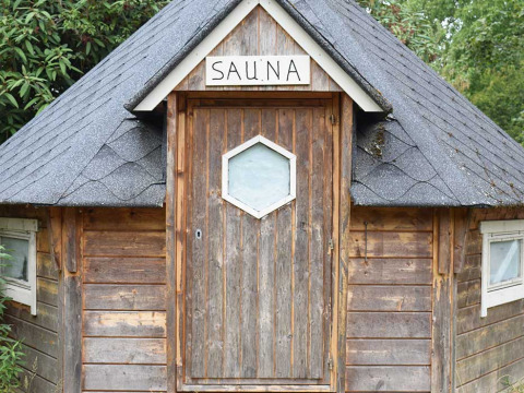 Sauna de madera con letrero, fotografiada en Feather Down Het Boshuis, parque vacacional en Gelderland, Países Bajos.