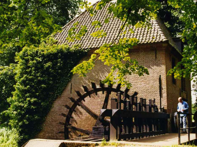 A historic watermill surrounded by greenery at Feather Down Het Boshuis in Gelderland, Netherlands.