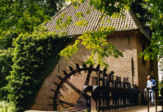 Een historische watermolen omringd door groen bij Feather Down Het Boshuis in Gelderland, Nederland.