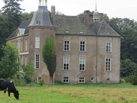 A historic brick house with towers in a green field, Feather Down Het Boshuis, Gelderland, Netherlands.