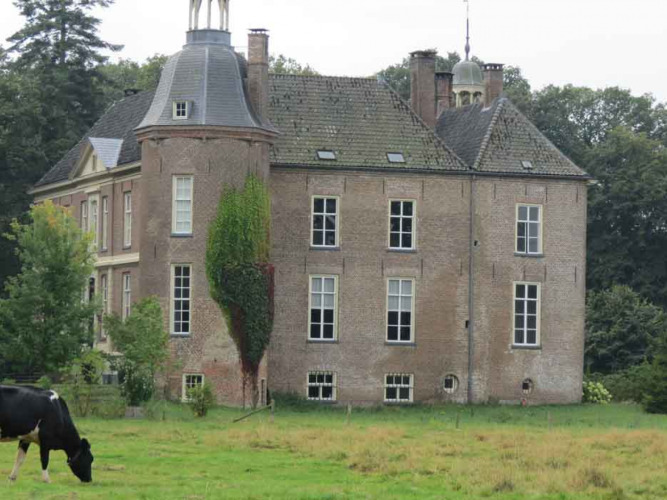 A historic brick house with towers in a green field, Feather Down Het Boshuis, Gelderland, Netherlands.