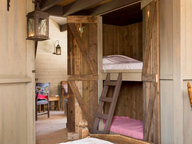 Cozy interior with wooden bunk beds and rustic decor at Feather Down Het Boshuis holiday park in Gelderland.