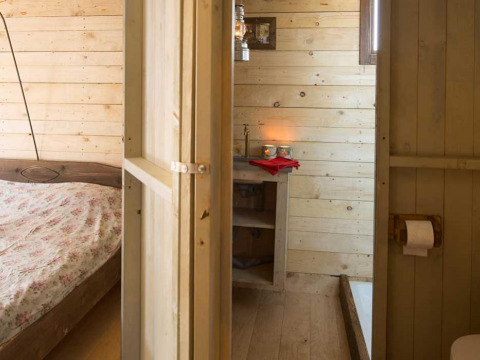 Dormitorio y baño con paneles de madera y decoración rústica en Feather Down Het Boshuis, Gelderland.