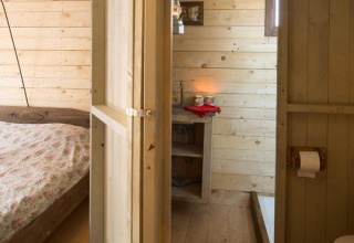 Houten slaapkamer en badkamer met landelijke inrichting bij Feather Down Het Boshuis, Gelderland, Nederland.