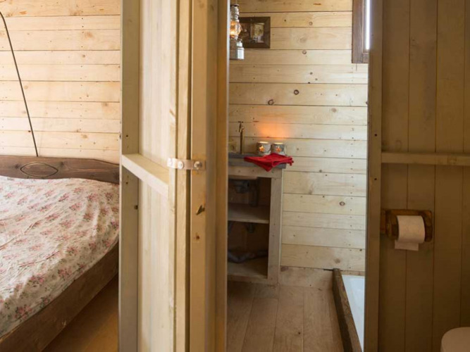 Wood-paneled bedroom and bathroom with rustic decor at Feather Down Het Boshuis, Gelderland, Netherlands.