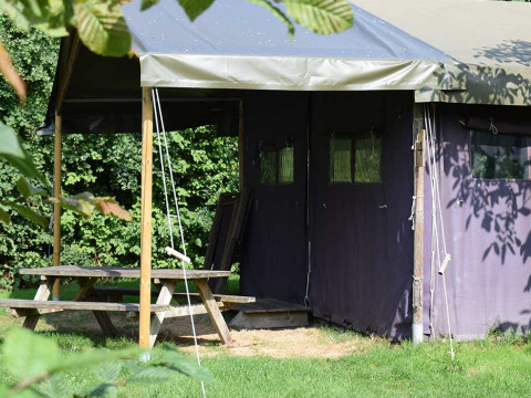 Outdoor covered tent and wooden picnic table at Feather Down Hoeve Zeeland holiday park in Zeeland, Netherlands.