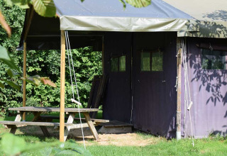 Udendørs campingområde med overdækket telt og træbord-bænkesæt på Feather Down Hoeve Zeeland i Holland.