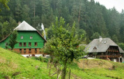 Two rustic houses nestled among trees and grassy hills at Feather Down Hilserhof, Baden-Württemberg, Germany.