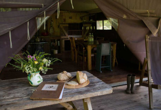 Rustiek tentinterieur in Feather Down Hilserhof met brood, weidebloemen en houten meubilair.