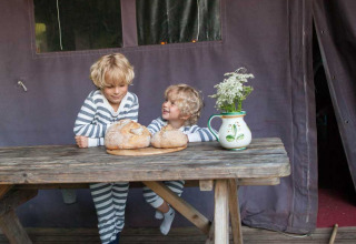 To børn i stribede pyjamas sidder ved et bord med brød og en vase blomster på Feather Down Hilserhof.